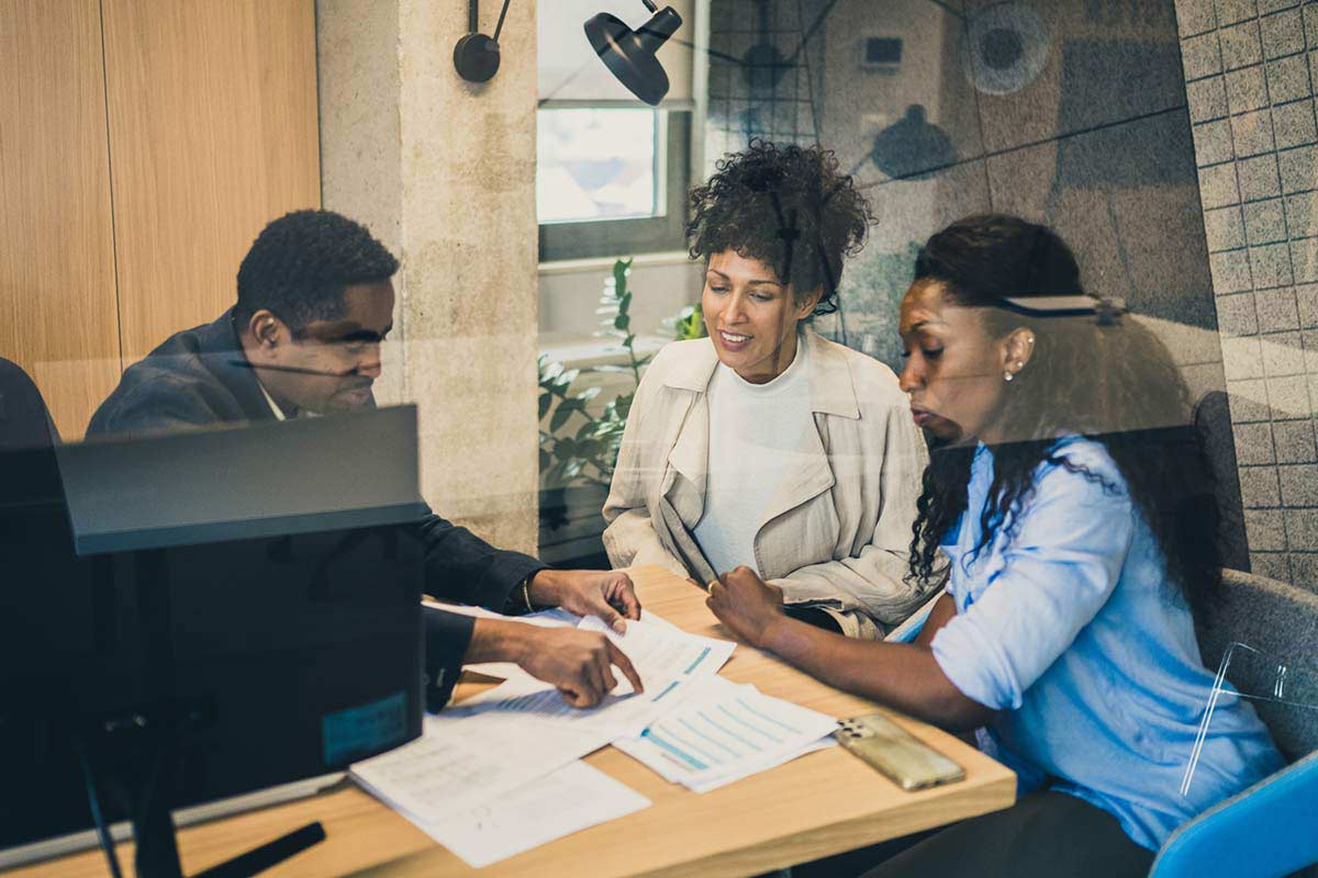 A bank employee explains paperwork to his customers
